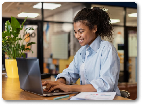 Mulhr trabalhando e sorrindo em frente ao notebook.